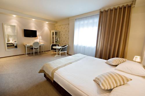 a hotel room with a large bed and a desk at Hotel Prezydencki 4-star in Rzeszów