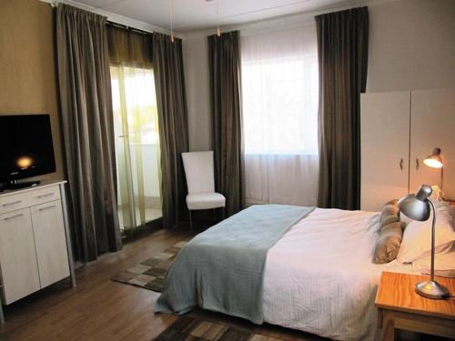 a bedroom with a bed and a desk and a television at Pebble Stone House Bed & Breakfast in Swakopmund