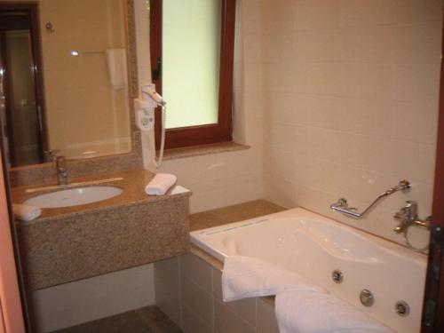 a bathroom with a tub and a sink and a mirror at Vila Codrin Neptun-Olimp in Neptun