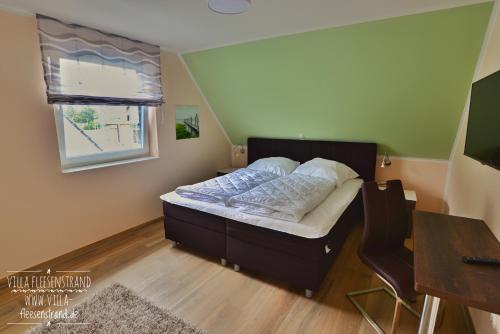 Schlafzimmer mit einem Bett, einem Tisch und einem Fenster in der Unterkunft Villa Fleesenstrand in Göhren-Lebbin