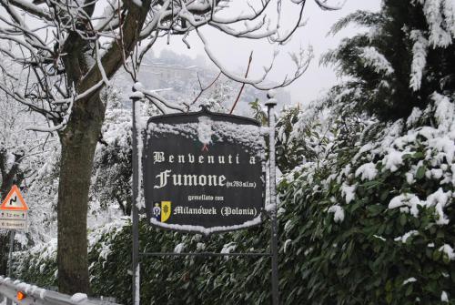 a sign with snow on it in front of some trees at Locanda Il Falco Nero in Fumone