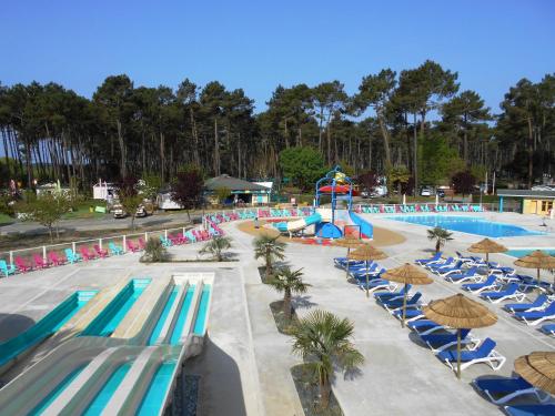 a pool with chairs and a water slide at a resort at Camping Officiel Siblu Les Dunes de Contis in Saint-Julien-en-Born