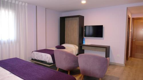 a hotel room with two beds and a television at Hotel Rural El Nido de Pinares in Navaleno