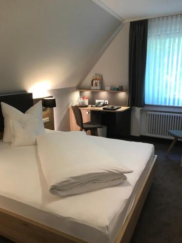 a bedroom with a white bed and a desk at Forellenhof Rössle Hotel & Restaurant in Honau