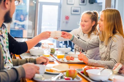 Auberge de Jeunesse de Namur في نامور: مجموعة من الأشخاص يجلسون حول طاولة ويتناولون الطعام