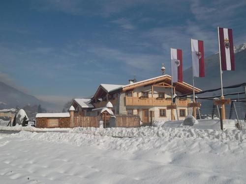 a building in the snow with flags on it at Agriturismo Maso Grisun in Borzago