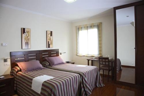 a bedroom with a large bed with a striped blanket at Hotel O Casino da Rasa in Nogueira de Ramuin