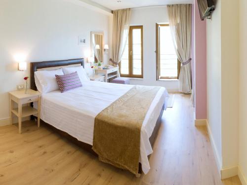 a bedroom with a large white bed and a desk at Arktos Hotel in Ioannina