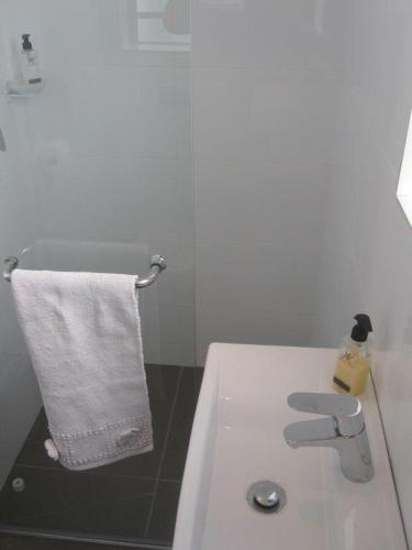 a white bathroom with a sink and a white towel at 20 belladonna avenue Vredehoek Cape town in Vredehoek