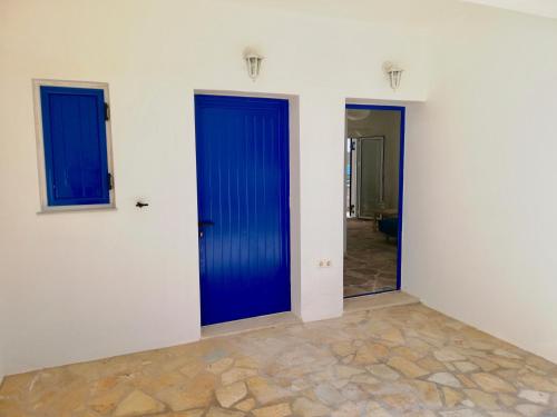 2 blaue Türen in einem Zimmer mit Fliesenboden in der Unterkunft SempreViva Sea Houses in Diakofti