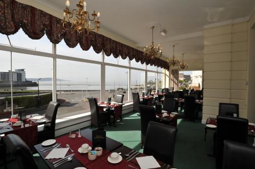 a restaurant with tables and chairs and a large window at New Birchfield Hotel in Weston-super-Mare