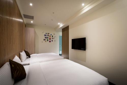 a bedroom with two beds and a flat screen tv at Merryday Hotel Banqiao in Taipei