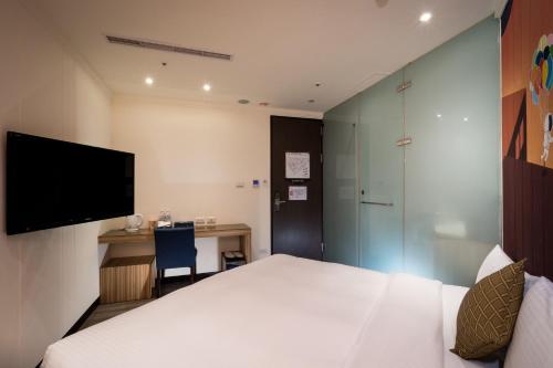 a hotel room with a bed and a desk and a tv at Merryday Hotel Banqiao in Taipei