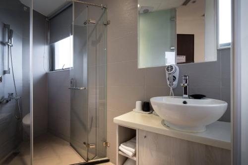 a bathroom with a sink and a glass shower at Merryday Hotel Banqiao in Taipei