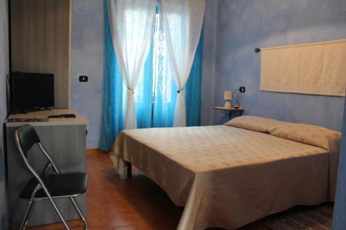 een slaapkamer met een bed, een bureau en een televisie bij Su Campanile in Baunei