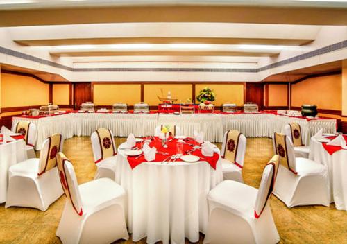 a large banquet hall with white tables and chairs at Ramoji Film City- Tara Comfort Hotel in Pedda Ambarpet