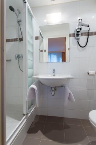 a white bathroom with a sink and a shower at Le Home in Vincennes