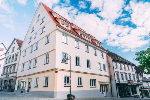 un edificio bianco con tetto rosso su una strada di Amtshaus Gut Hügle Boutique Apartments a Bad Waldsee