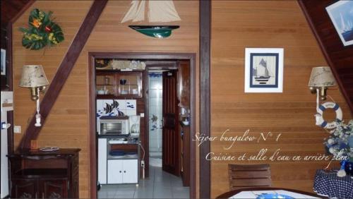 a room with wooden walls and a kitchen with a refrigerator at Les bungalows de la plage in La Trinité