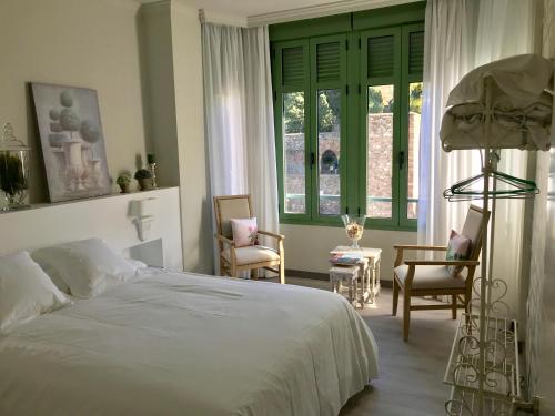 a bedroom with a bed and chairs and a window at Gr Suites Boutique Alcazaba in Málaga