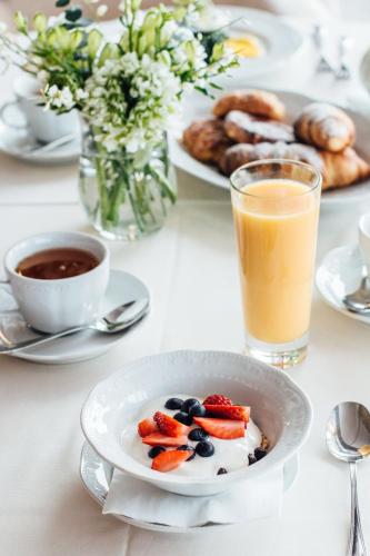 a table with a plate of fruit and a glass of orange juice at Boutique Hotel Light House Jurmala in Jūrmala