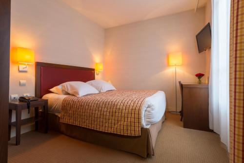 a hotel room with a bed and two lamps at Le Home in Vincennes