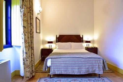 a bedroom with a bed with a striped blanket and a window at Central Monchique Hotel - Villa Termal Spa Resort - by Unlock Hotels in Monchique