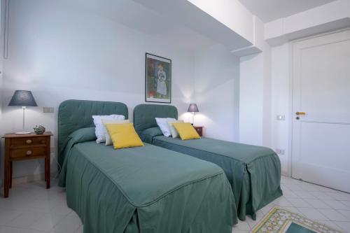 a bedroom with two beds with green sheets and yellow pillows at Villa dei Limoni con terrazza e discesa a mare in Erchie