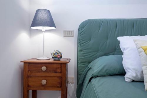 a lamp on a night stand next to a green bed at Villa dei Limoni con terrazza e discesa a mare in Erchie