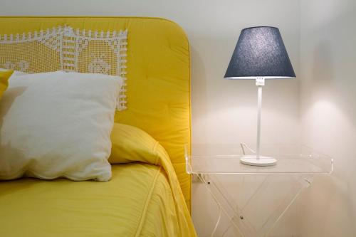 a bed with a yellow headboard and a table with a lamp at Villa dei Limoni con terrazza e discesa a mare in Erchie