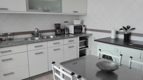 a white kitchen with a sink and a stove at Alojamento S. Pedro in Peniche