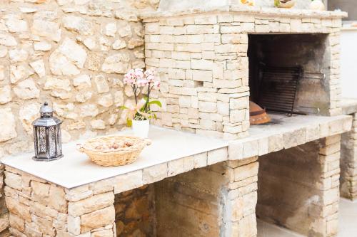 a stone fireplace with a basket and flowers on a counter at Guest House Mara in Vela Luka