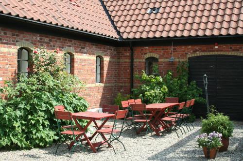 a patio with red tables and chairs in front of a brick building at Blåsingsborgs Gårdshotell in Kivik