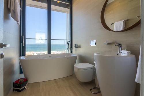 een badkamer met een bad, een toilet en een raam bij Nyota Hotel & Conference Center in Mamaia
