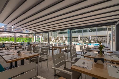 a restaurant with tables and chairs and a pool at Nyota Hotel & Conference Center in Mamaia