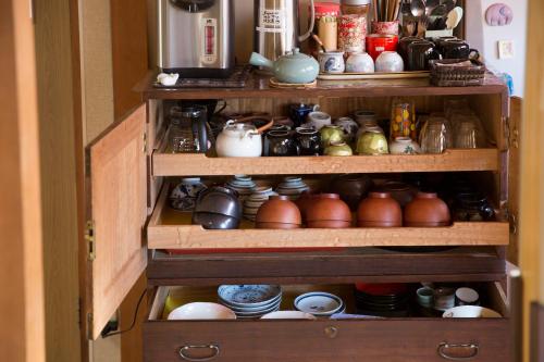 a wooden cabinet filled with lots of pots and pans at Guest House Pongyi in Kanazawa