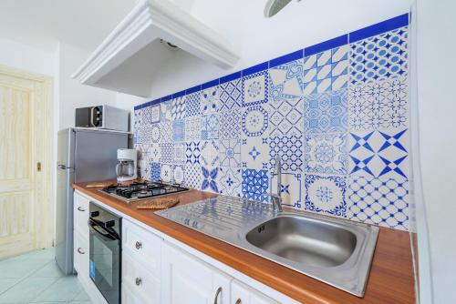 a kitchen with a sink and blue and white tiles at Casa TerryB - il Monticello in Positano