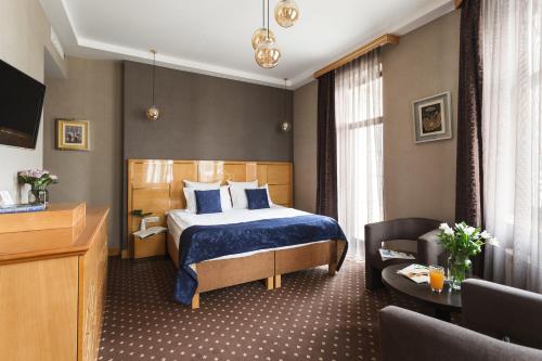 um quarto de hotel com uma cama e uma cadeira em Ark Palace Hotel & SPA em Odessa