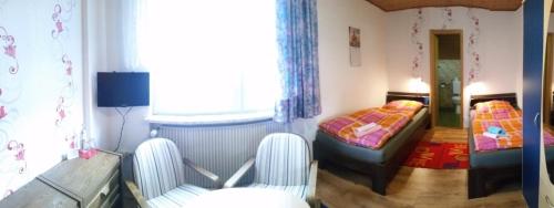 a small room with two beds and two chairs at Hotel-Pension Dressel in Warmensteinach