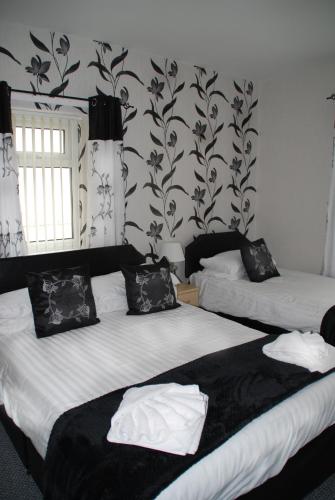 a bedroom with two beds with black and white wallpaper at Brincliffe Hotel in Blackpool
