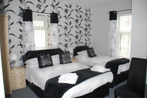 two beds in a bedroom with black and white wallpaper at Brincliffe Hotel in Blackpool