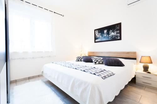 a white bedroom with a large bed and a window at Guest House Mara in Vela Luka