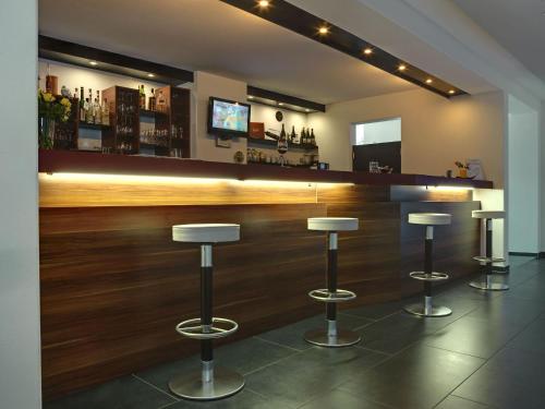 a bar with three stools in a room at Allgäuhotel Memmingen Nord in Memmingen