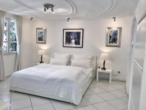 a white bedroom with a white bed and two lamps at Kramwinkelsuite Regensburg in Regensburg