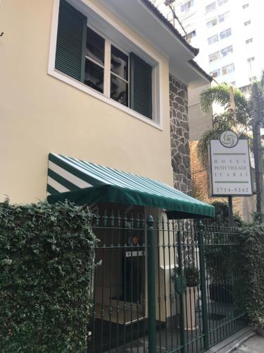 a building with a green awning next to a fence at Hotel Petit Village Icaraí in Niterói