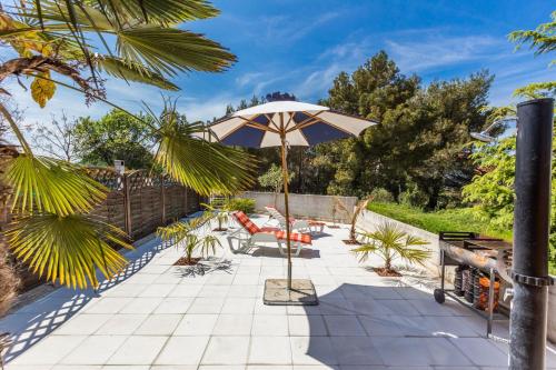 a patio with an umbrella and chairs and a table at Holliday Home MaxDom in Sukošan