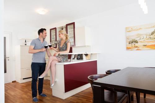 a man standing next to a woman sitting on a counter at Hotel Sandwirth in Klagenfurt
