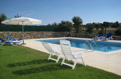 un grupo de sillas y una sombrilla junto a una piscina en Quinta de la Barandica, en Miranda do Douro