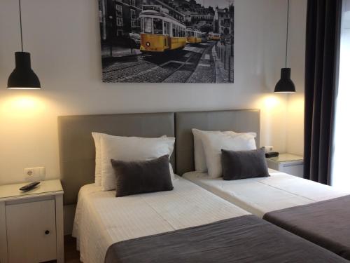 a hotel room with two beds and a yellow streetcar at Anjo Azul in Lisbon