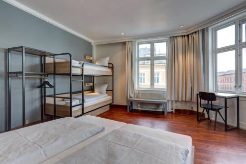 a bedroom with two bunk beds and a desk at Urban House Copenhagen by MEININGER in Copenhagen